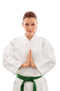 Woman in martial arts uniform standing at attention, wearing a green belt