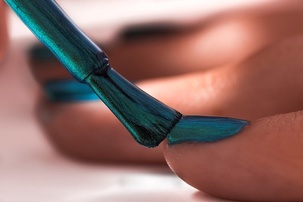 Applying teal fingernail polish