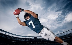 Football player leaping forward and catching the ball