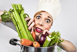 Harried looking chef peering between vegetables