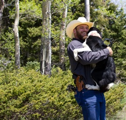 Grinning cowboy holding his ranch dog