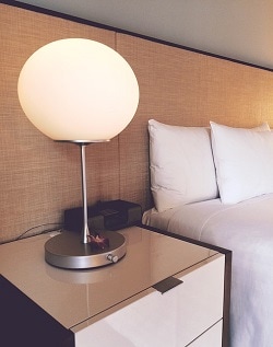 Hotel room side table with lamp beside bed