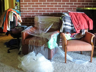 half wrapped furniture with piles of clothes