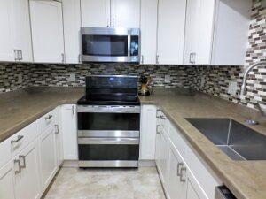 Picture of our new kitchen counters, sink, microwave, backsplash, sink, and cabinets